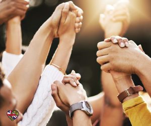 Several people standing together with raised, clasped hands, symbolising community, teamwork and mutual support.